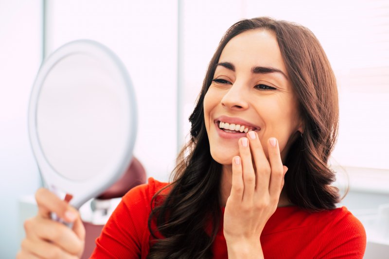 Patient smiling in a mirror after replacing their dental fillings